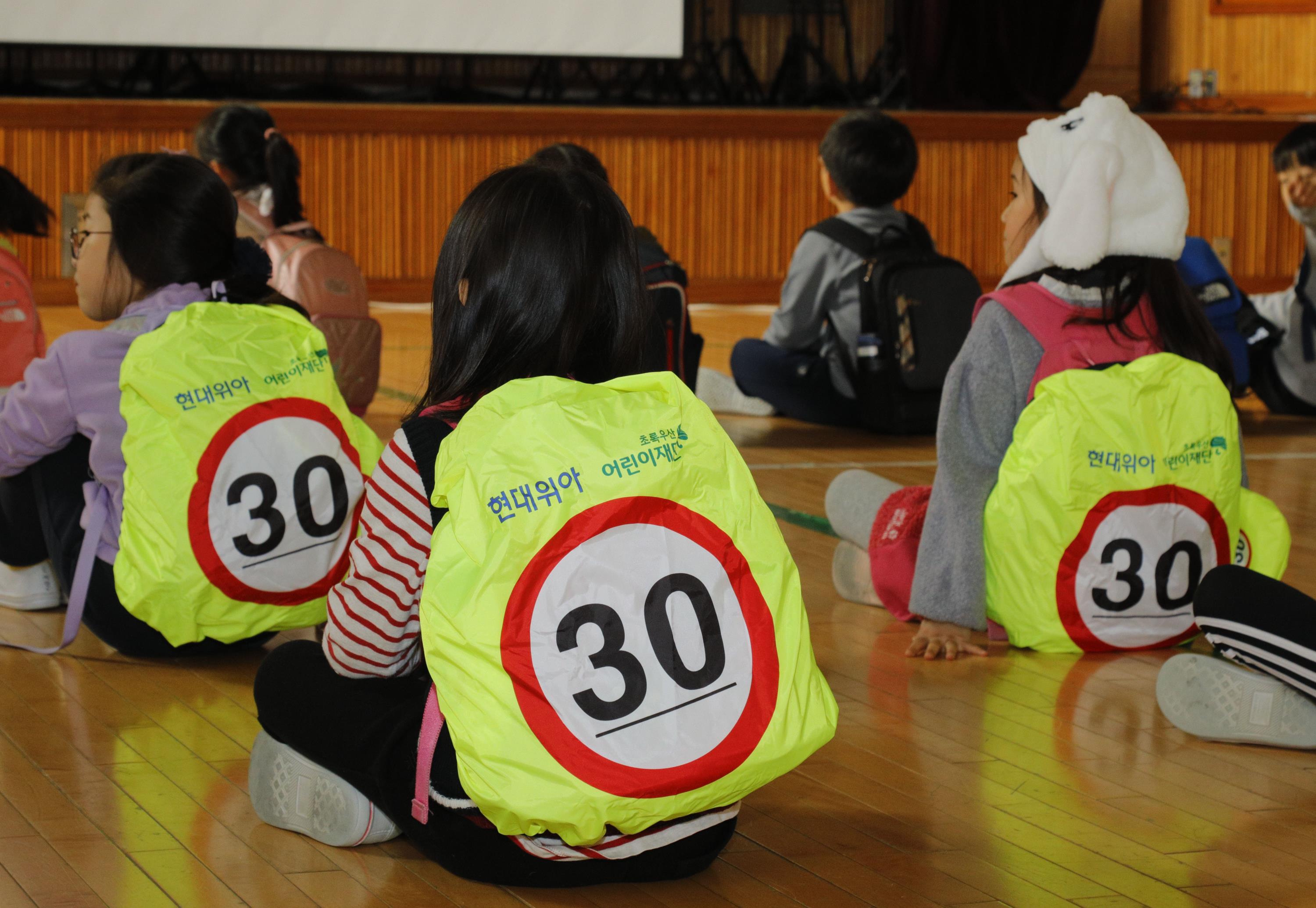 18일 경상남도 창원시 삼정자초등학교 학생들이 현대위아가 선물한 ‘교통안전 가방덮개’가 덮인 가방을 메고 있다.