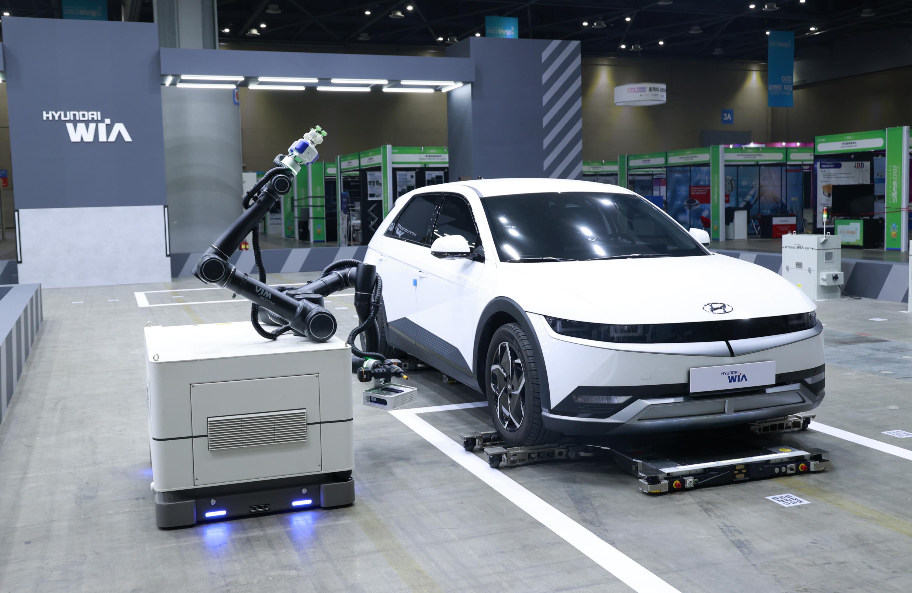 현대위아가 11일 경기도 고양시 KINTEX에서 열린 ‘로보월드 2023’에서 공개한 주차로봇의 모습. 얇고 넓은 주차로봇이 자동차를 들어 올려 주차하고 있다.