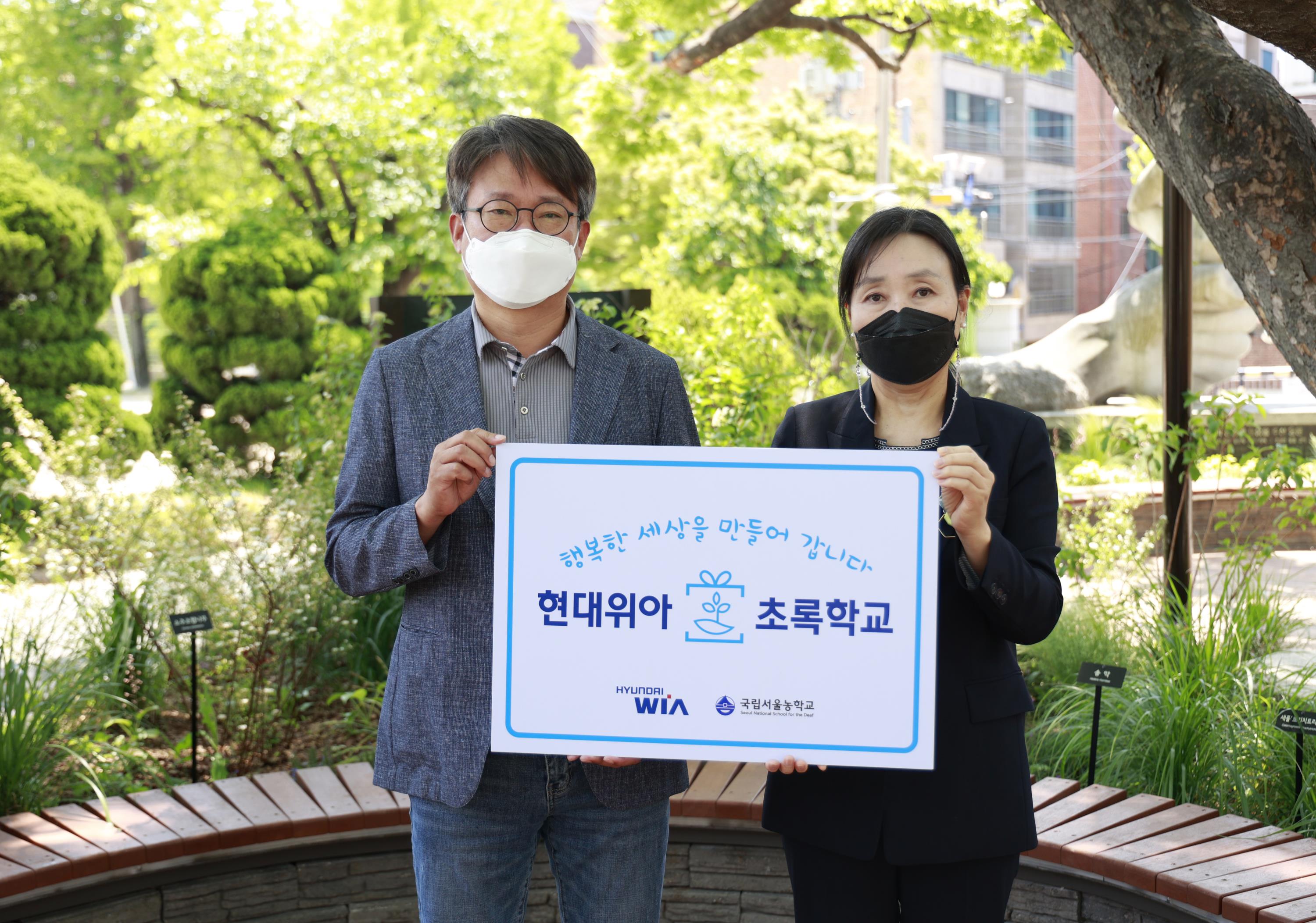 현대위아 원광민 차량부품연구센터장과 국립서울농학교 김은숙 교장이 지난 10일 서울 종로구 국립서울농학교 내 현대위아가 조성한 ‘느티나무 정원’에서 기념사진을 찍고 있다.