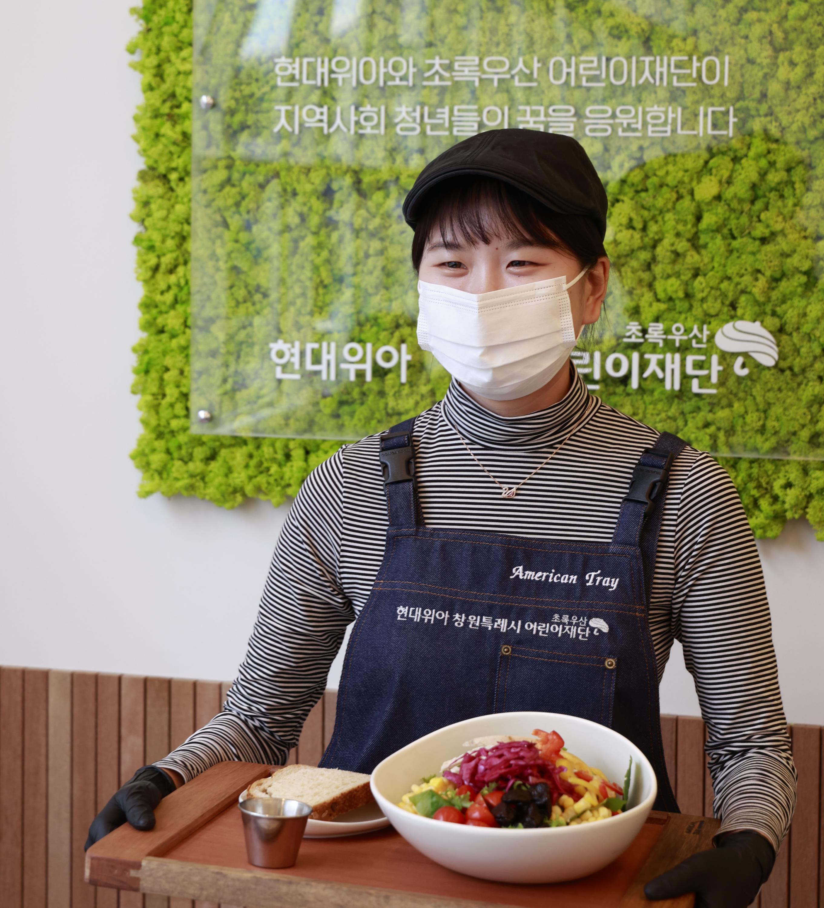 현대위아가 26일 자립준비청년의 경제적‧정서적 자립을 돕기 위해 만든 ‘현대위아 청년일터’에서 한 직원이 직접 만든 샐러드를 선보이고 있다.