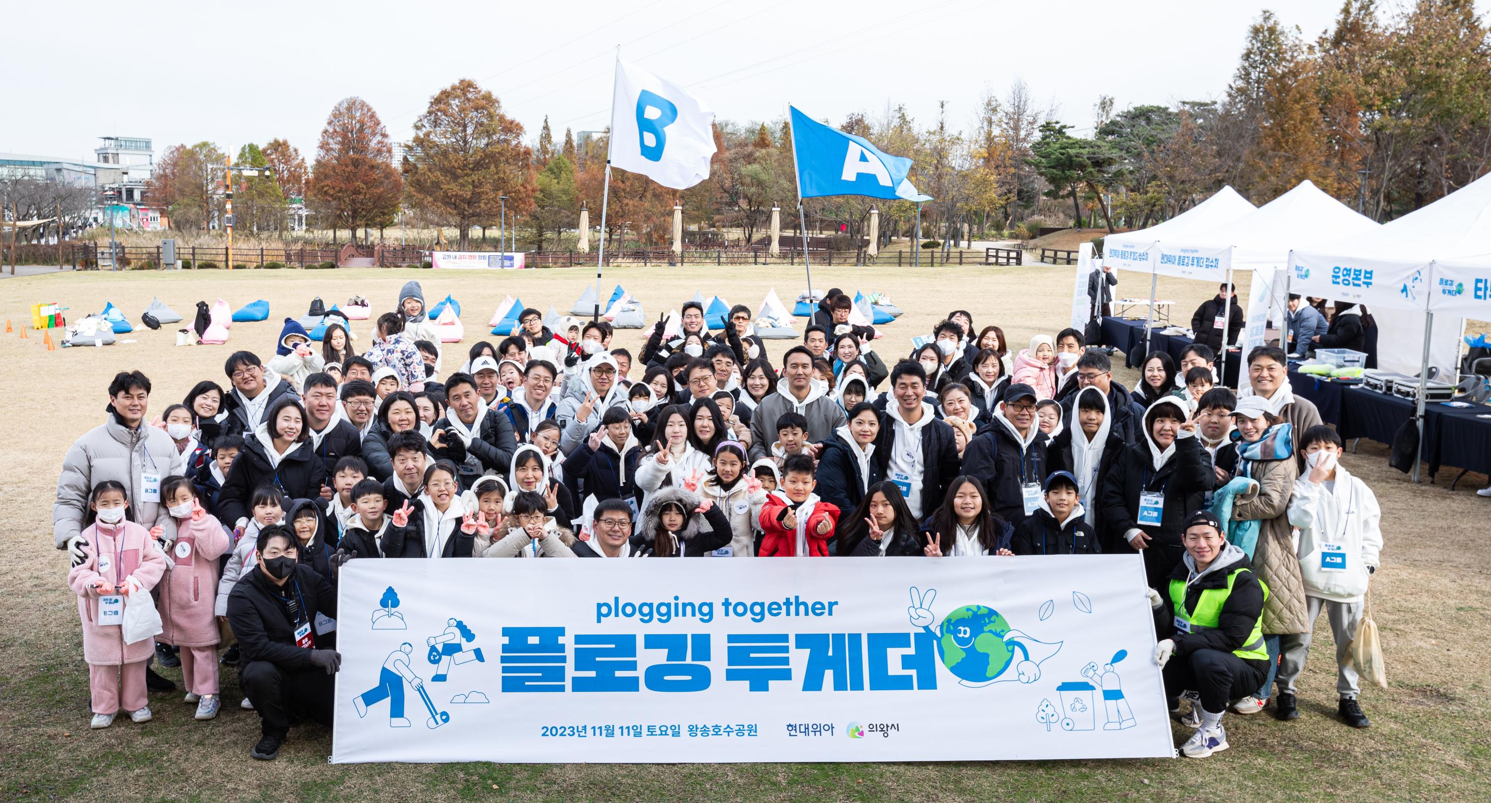 현대위아 직원 및 가족들이 11일 경기도 의왕시 왕송호수공원에서 ‘플로깅(Plogging)’ 봉사 기념 사진을 찍고 있다.
