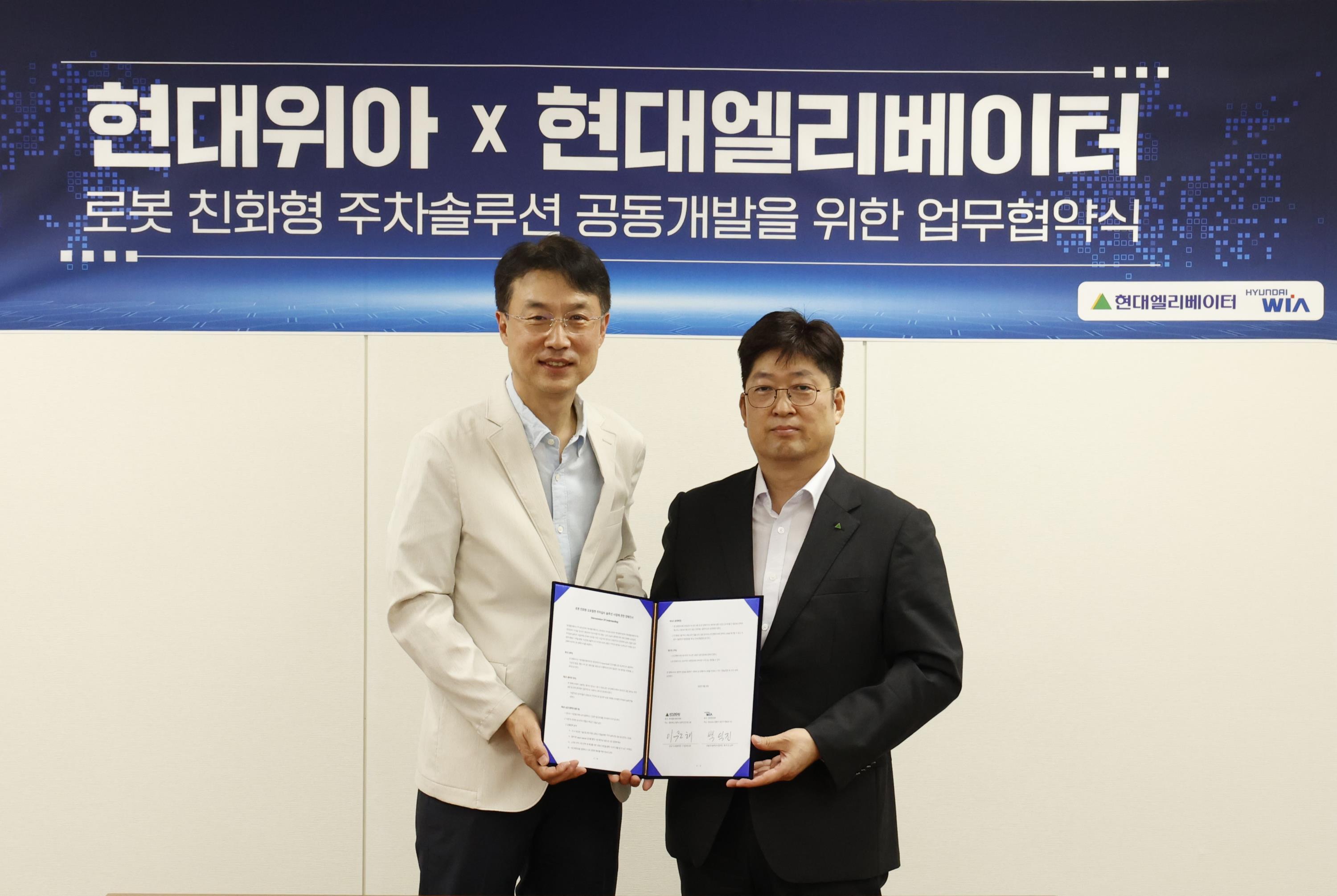 현대위아 모빌리티솔루션사업부 백익진 상무(왼쪽)와 현대엘리베이터 승강기사업본부장 이원해 상무가 28일 경기도 의왕시 현대위아 의왕연구소에서 열린 ‘로봇 친화형 주차솔루션 공동개발을 위한 업무협약식’에서 기념 사진을 찍고 있다.